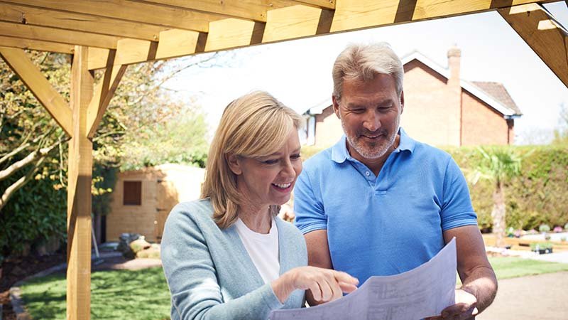 Dame og mann sjekker arbeidstegning for bygging av pergola.